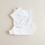 White yoga pants shorts scrunch bum leggings folded neatly on a neutral surface, top-down flat lay view.