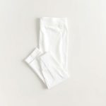 Flat lay of black wide leg yoga pants with subtle scrunch detail, white colour, neatly folded on a neutral surface.