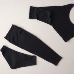 Flat lay of female leggings with pockets in charcoal, neatly folded on a neutral surface, black leggings black top.