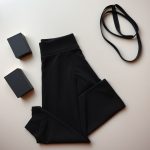 Flat lay of flare black yoga pants with yoga blocks and straps, neatly folded on a neutral surface.