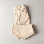 Flat lay of beige Luna 3 flare stretch pants folded on a neutral surface.