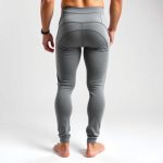 Back view of a model wearing high waisted yoga pants for guys in Heather Grey, studio shot on white background.