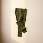 Flat lay of olive green Hilary yoga pants AUD to NRP folded on a neutral surface.