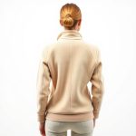 A model wearing a beige fleece womens golf jacket, back view, studio shot on white background.