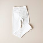 White scrunch bum workout pants with pockets, neatly folded on a neutral surface, top-down flat lay view.