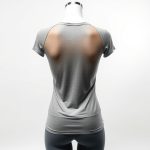 Back view of a model wearing a Heather Grey see through yoga tshirt, studio shot.